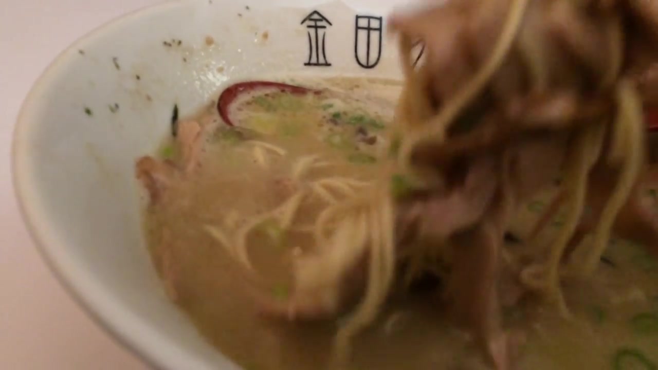 Thin ramen noodles lifted with chopsticks from tonkotsu broth