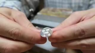Sterling silver cufflink with feature hallmarks held at the jeweller’s bench