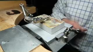 Cufflink components held at the jeweller’s bench for assembly