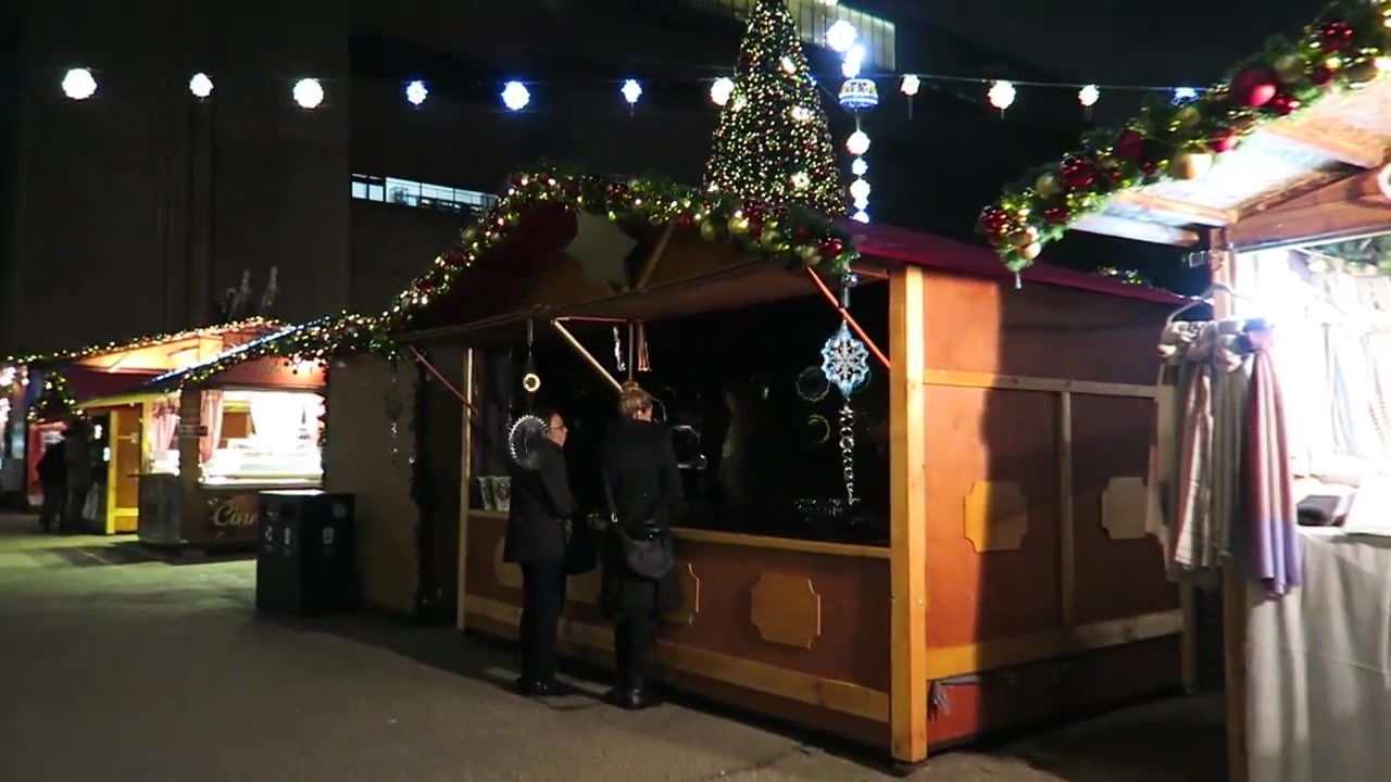 Wooden Christmas market chalets decorated with lights outside Tate Modern