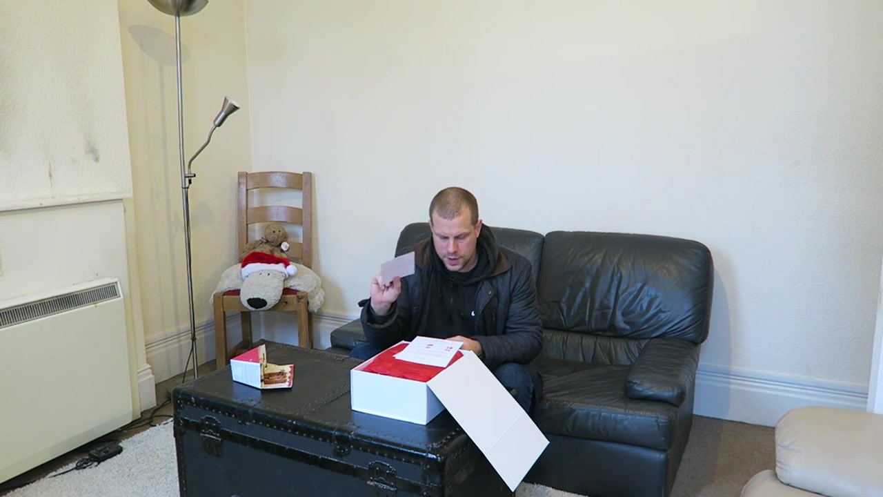 Barry opening a white gift box with red ribbon at home