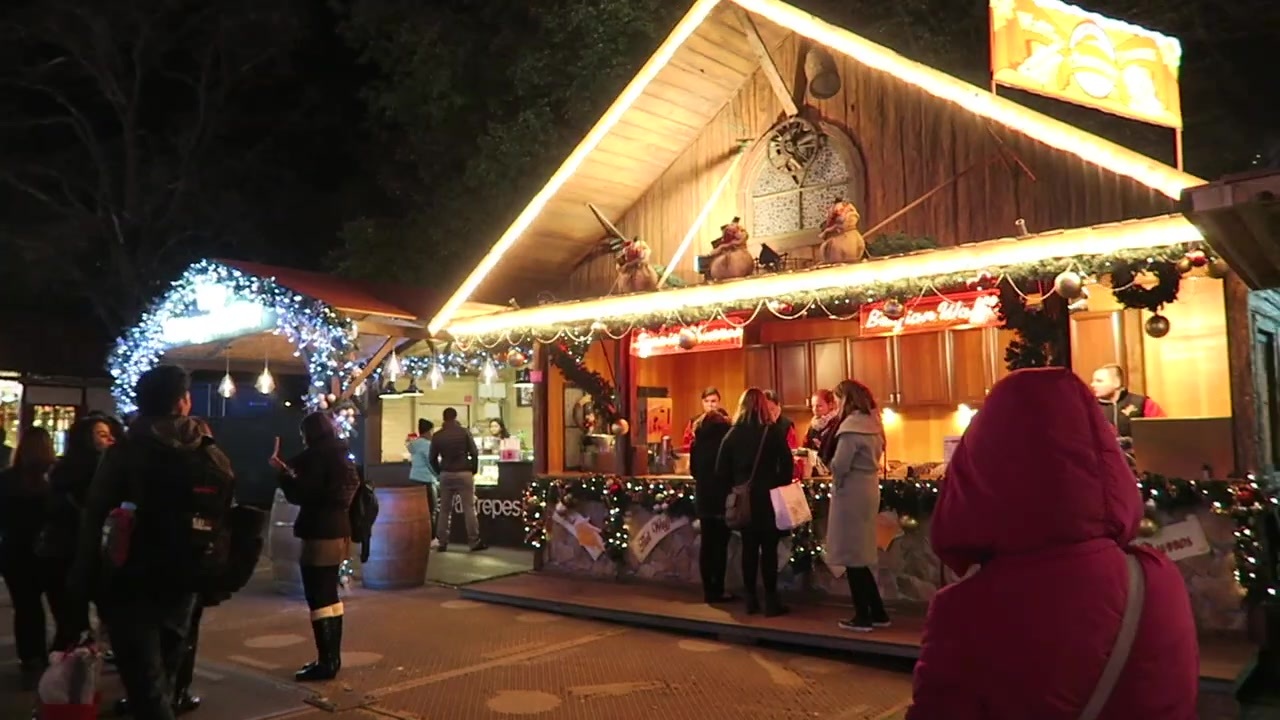 Illuminated wooden Christmas market hut with visitors outside