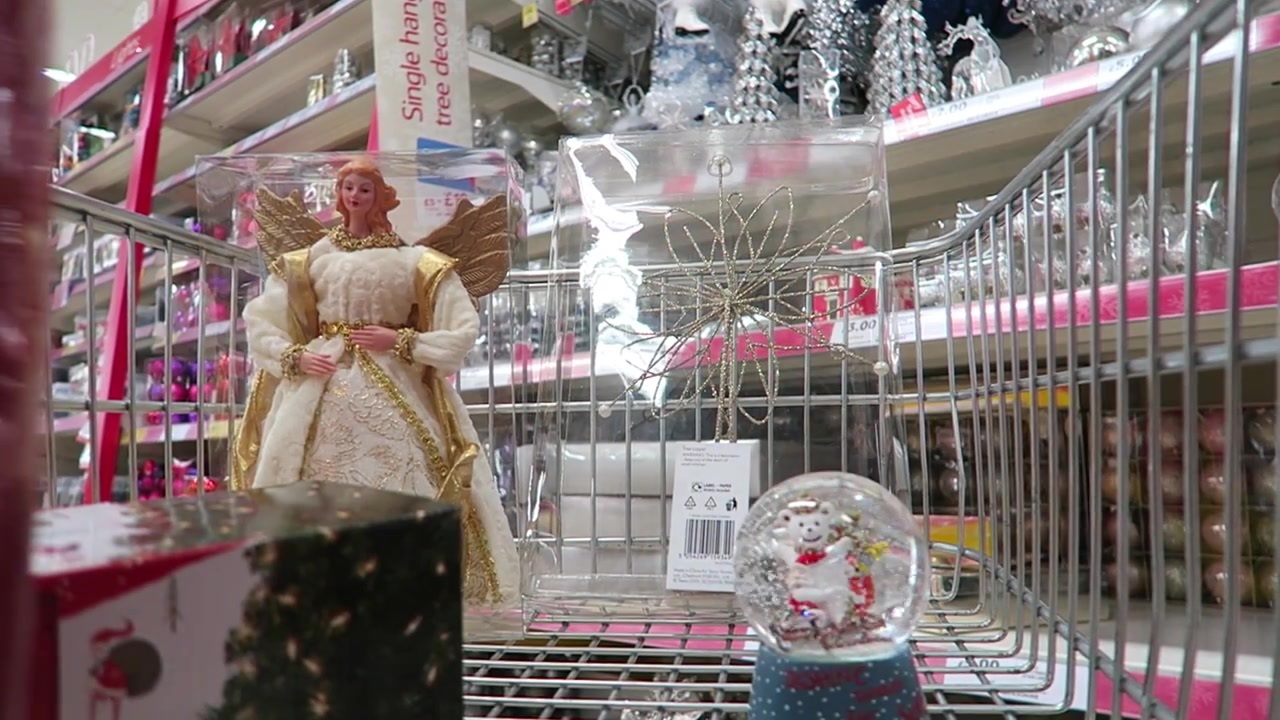 A Christmas angel, snow globe and other decorations beside a shopping trolley.