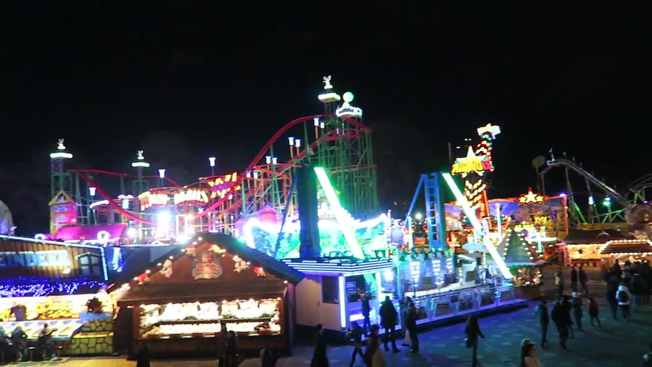 Colourful fairground rides illuminated against the night sky
