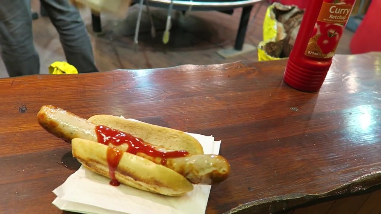 Bratwurst in a bread roll with sauce on a market counter