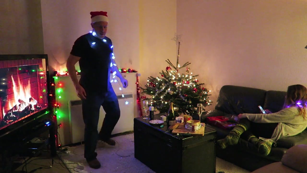 Barry wears a string of glowing star lights beside the decorated Christmas tree.