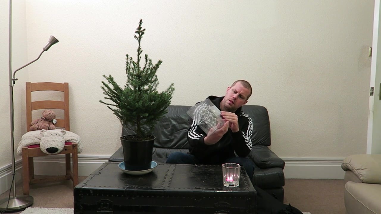 Barry examining a silver decoration beside the small Christmas tree