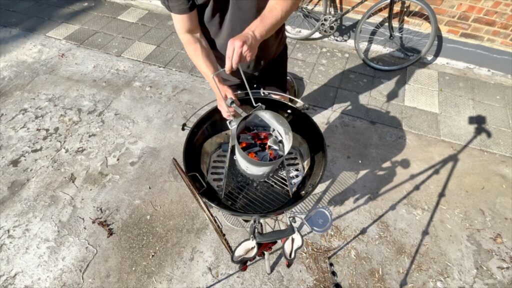 Barry Roberts preparing a Weber charcoal barbecue on a London rooftop