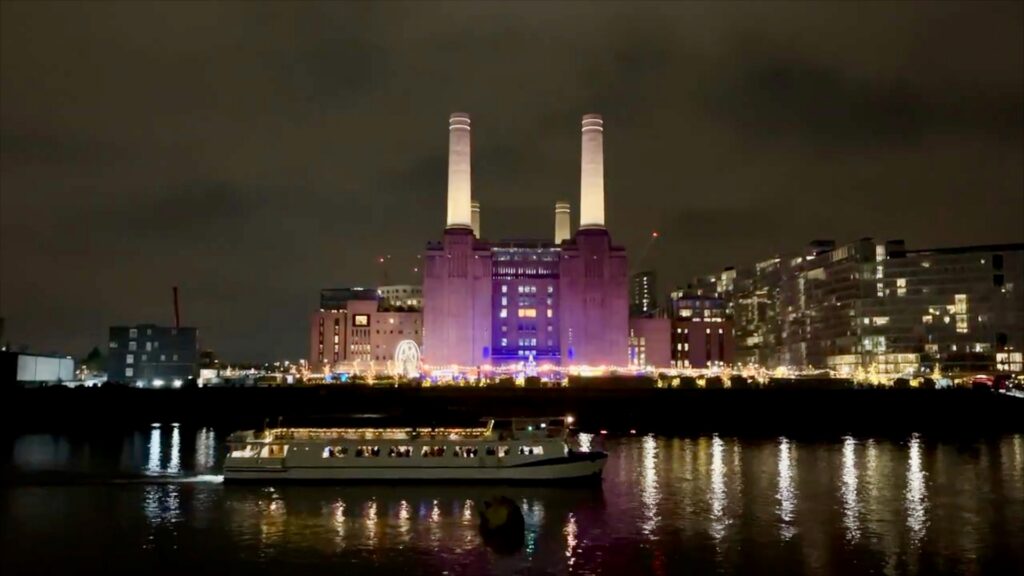 Battersea Power Station illuminated at night with festive decorations and Christmas trees in the surrounding public space