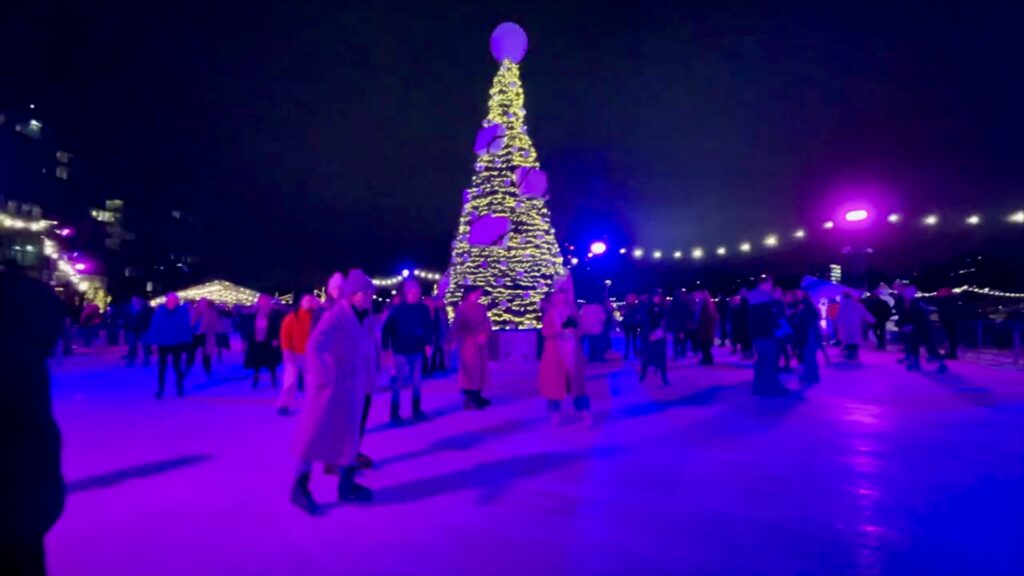 Ice skaters circling a Christmas tree on the seasonal rink beneath Battersea Power Station