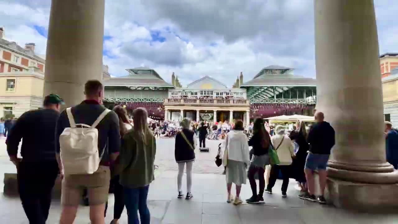 Visitors walking through Covent Garden Piazza beneath the historic market colonnades in central London