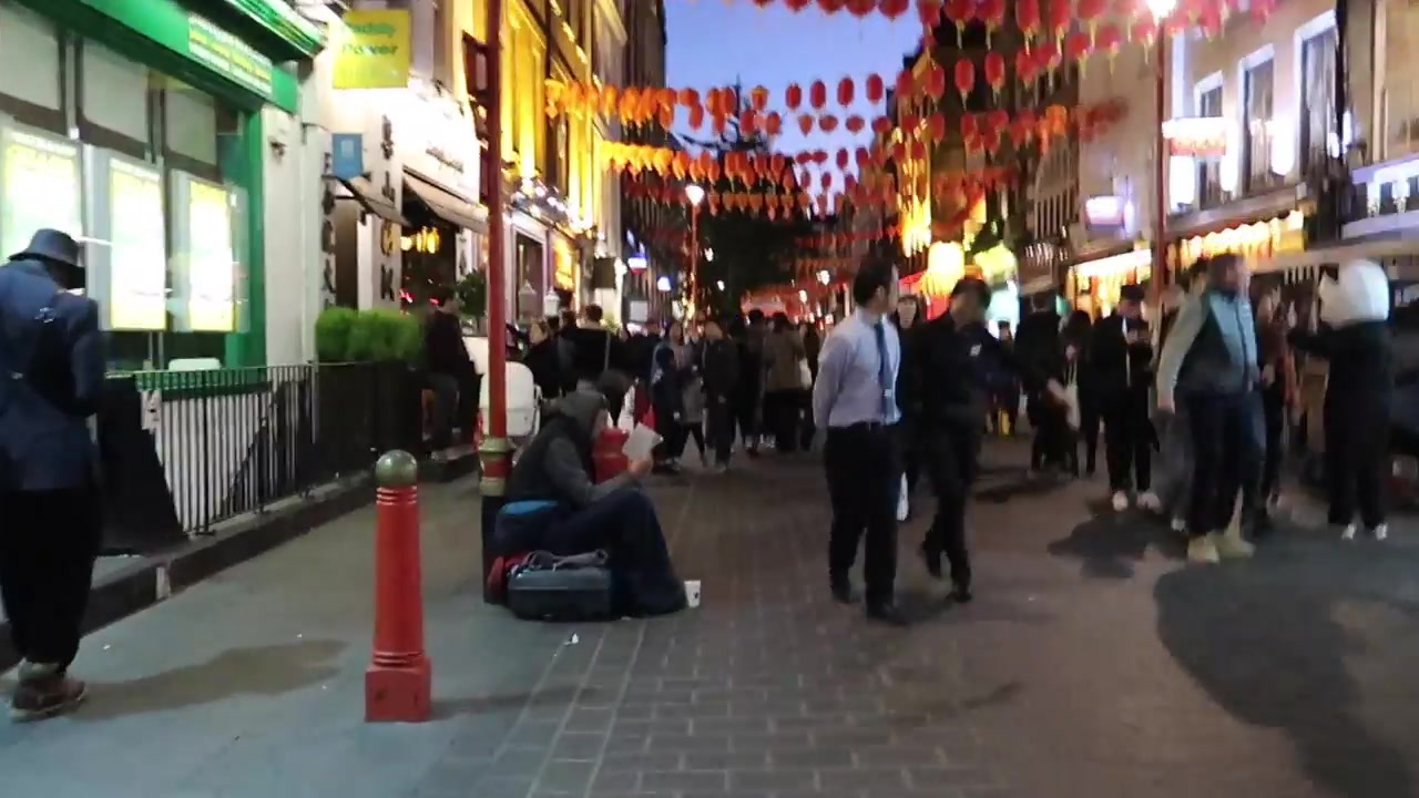 Illuminated Chinatown gate and red lanterns above a busy London street at night