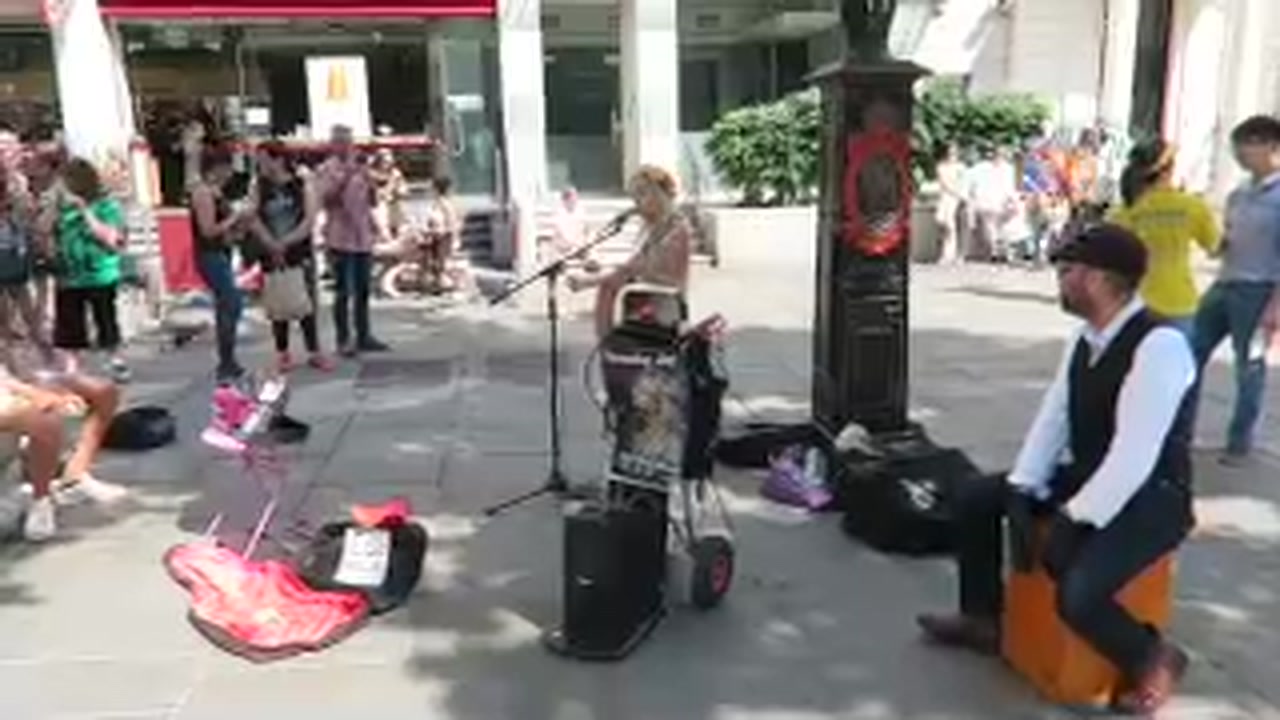 Singer and accompanying musician performing for a street audience in central London.