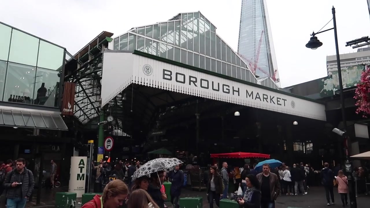 Crowds carrying umbrellas beneath the Borough Market entrance in London