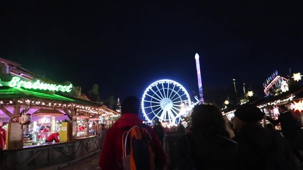 Illuminated observation wheel beyond Christmas market stalls at Hyde Park Winter Wonderland 2017