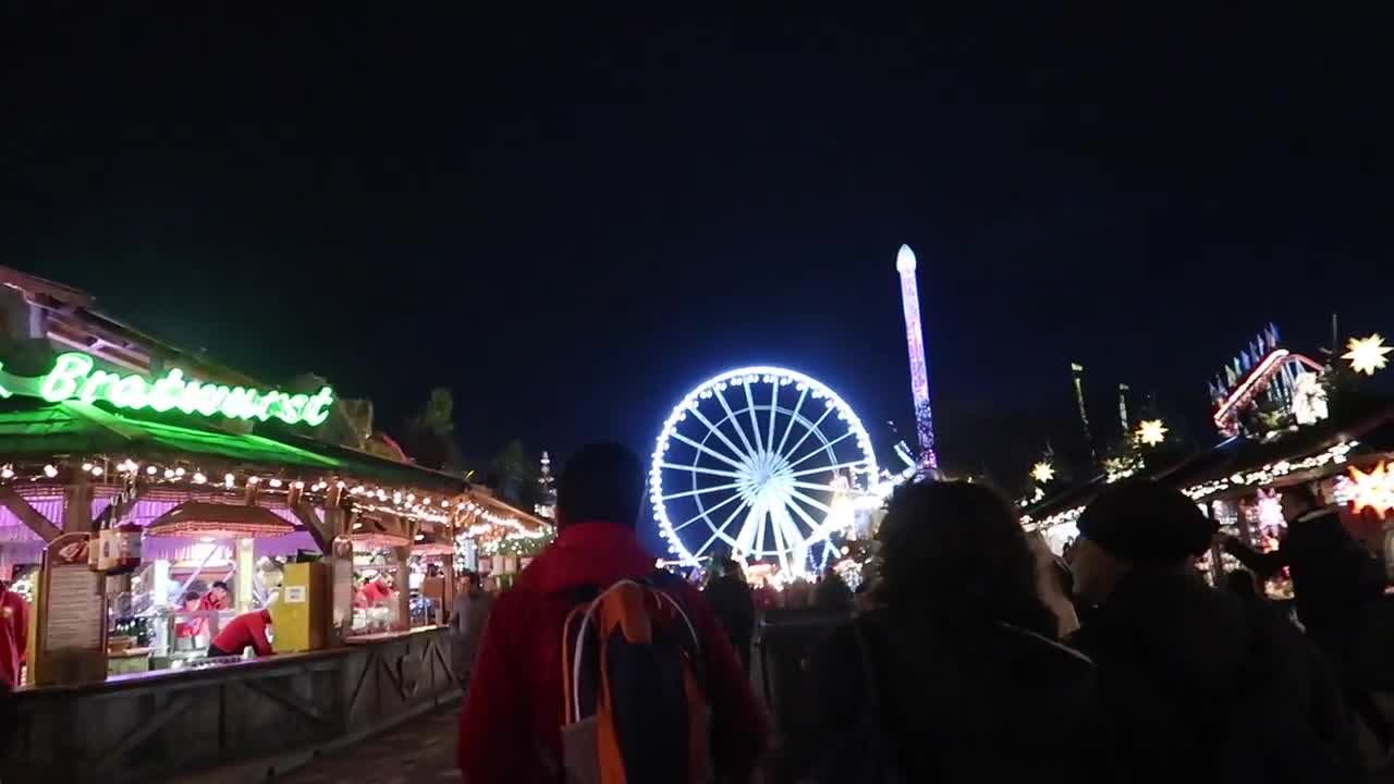 Illuminated observation wheel beyond Christmas market stalls at Hyde Park Winter Wonderland 2017