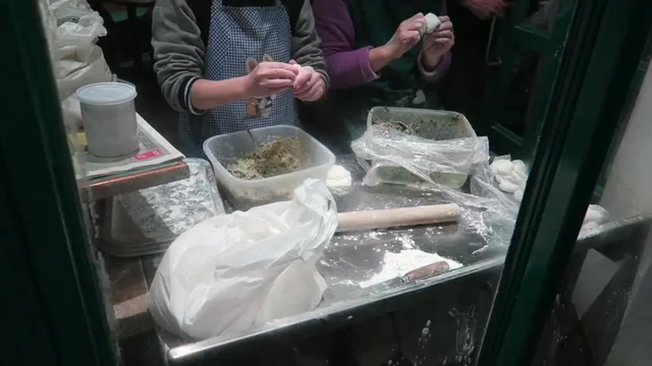 Two cooks folding fresh dumplings by hand inside Jen Café in Chinatown