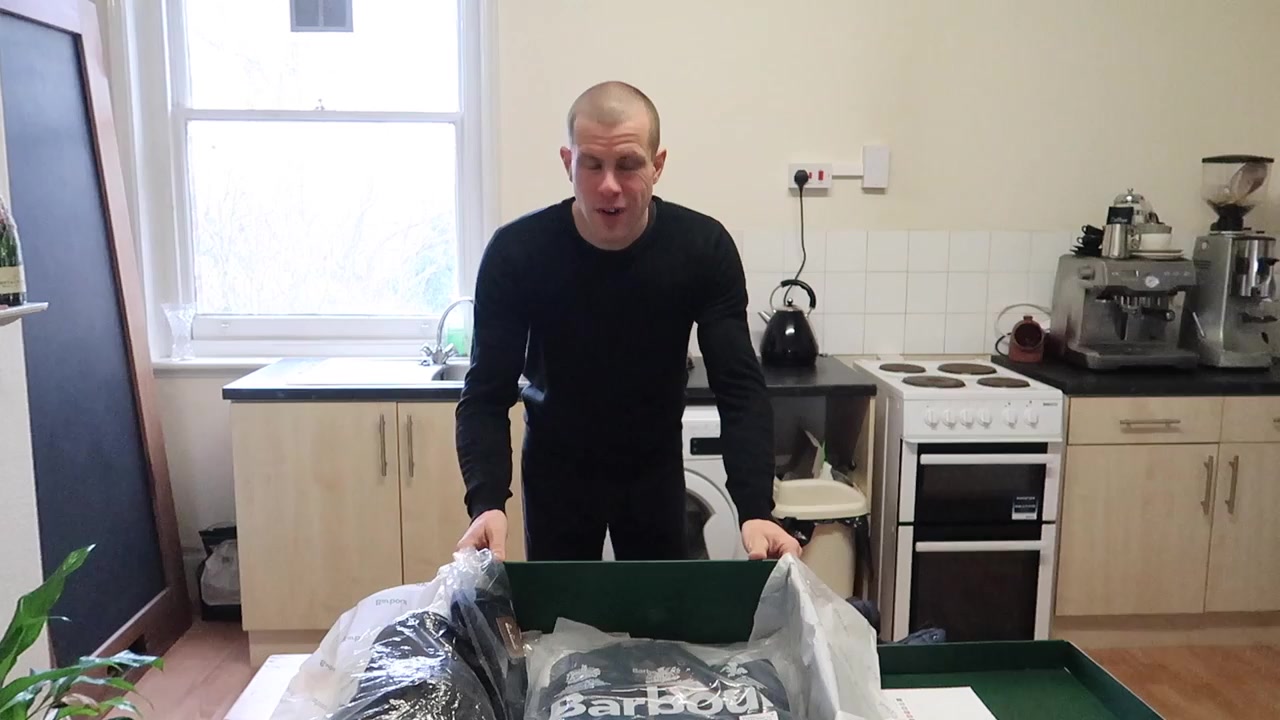 Barry Roberts opening a green Barbour delivery box during the 2018 wardrobe film.