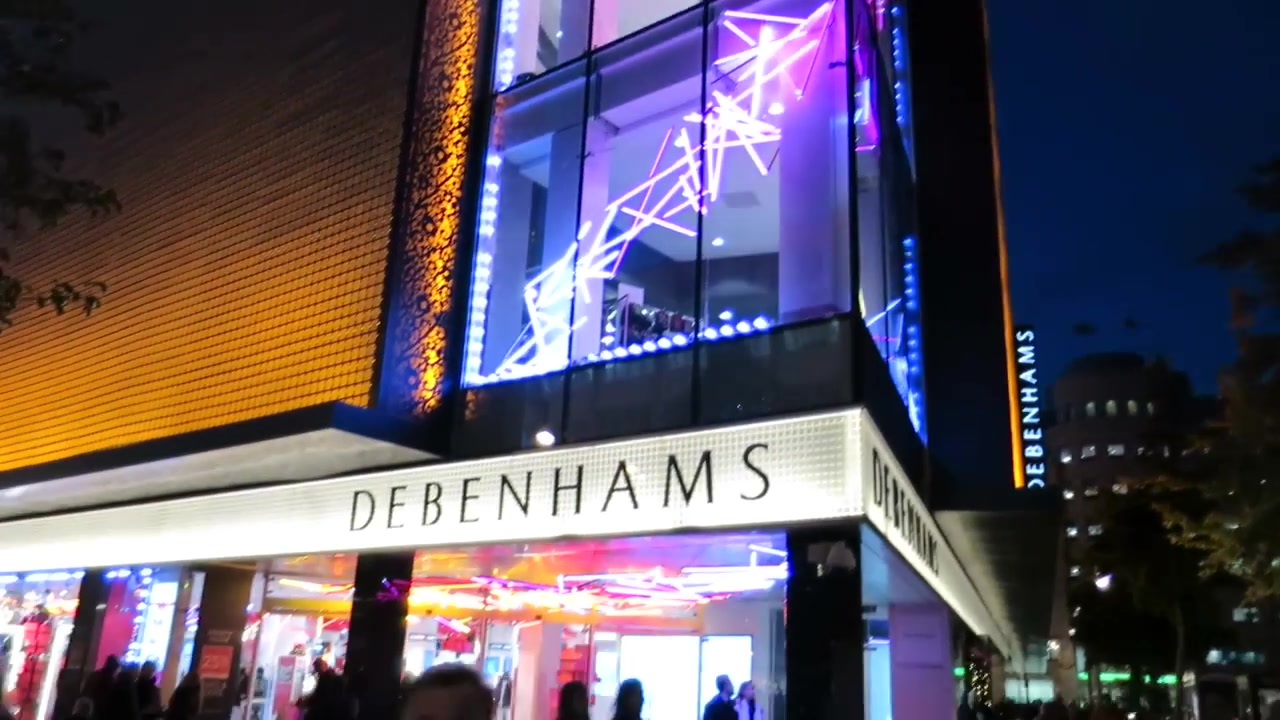 Illuminated Debenhams entrance and coloured Christmas lighting on Oxford Street in 2014.