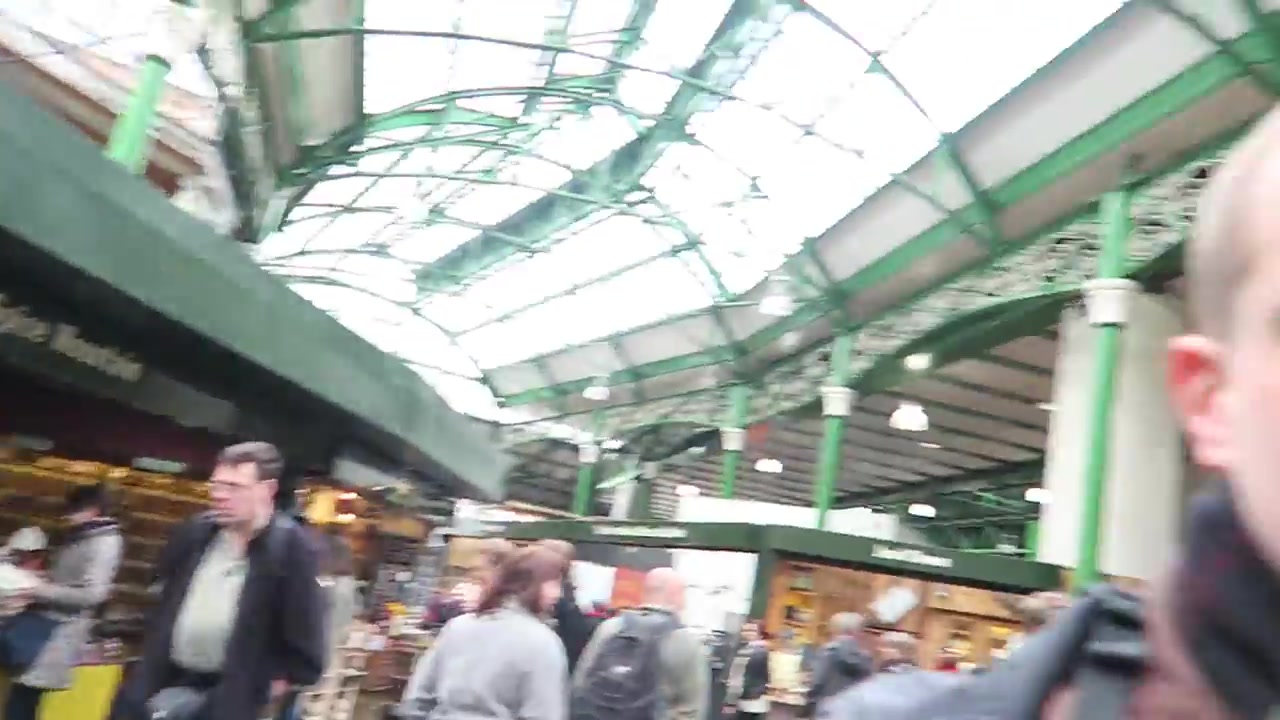 Shoppers beneath the green iron and glass roof of Borough Market