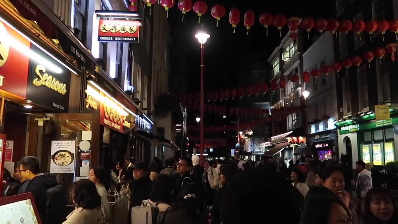 Evening crowds walking beneath red lanterns in London Chinatown in September 2018
