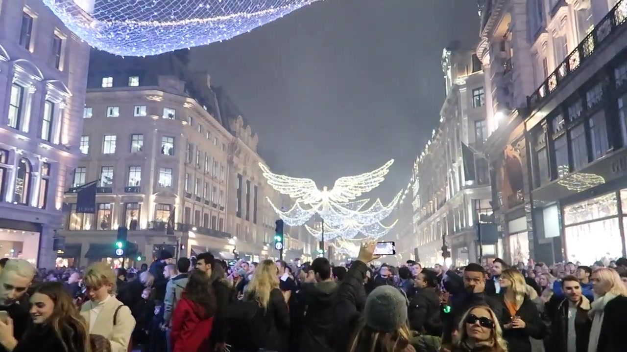 Crowd filling traffic-free Regent Street beneath the Christmas angel lights
