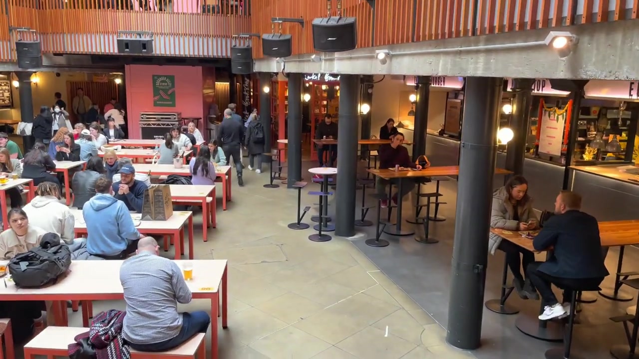 Seven Dials Market interior with communal tables, orange balustrades and food stalls around the atrium.