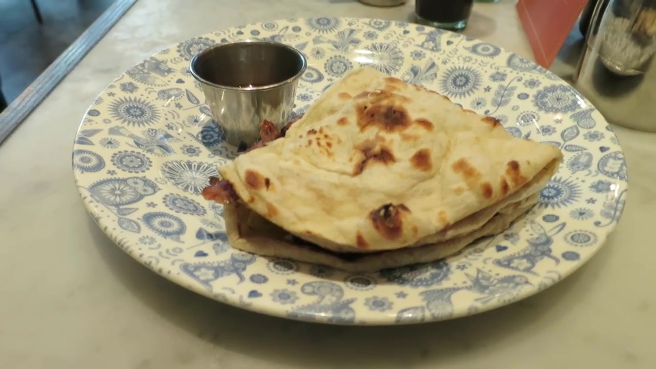 Dishoom bacon naan roll served on a patterned plate