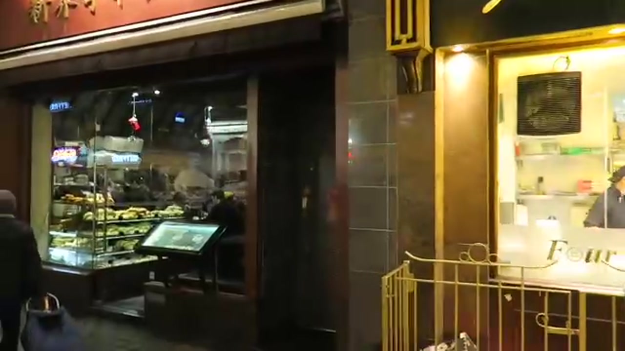 Illuminated bakery window and restaurant frontage in London’s Chinatown at night
