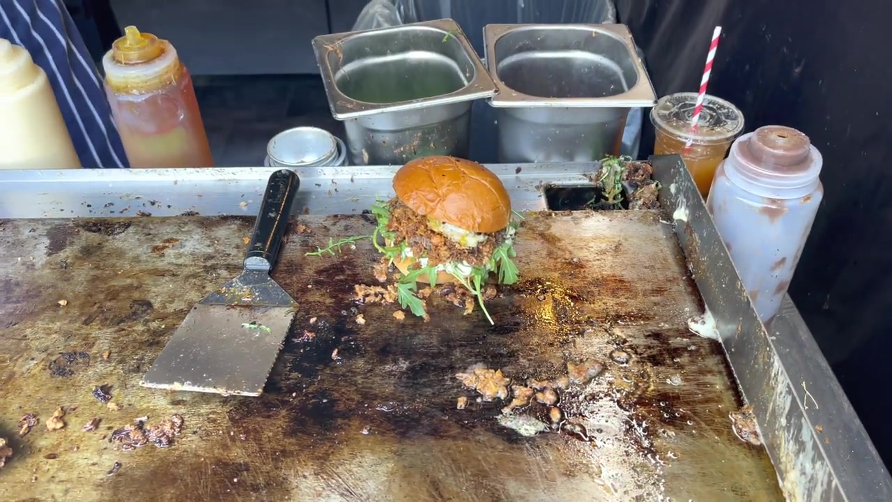 Completed duck confit burger with brioche bun and salad resting on The Frenchie griddle.