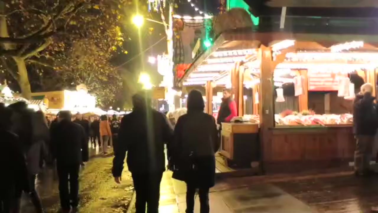 Visitors passing illuminated festive food stalls at Hyde Park Winter Wonderland