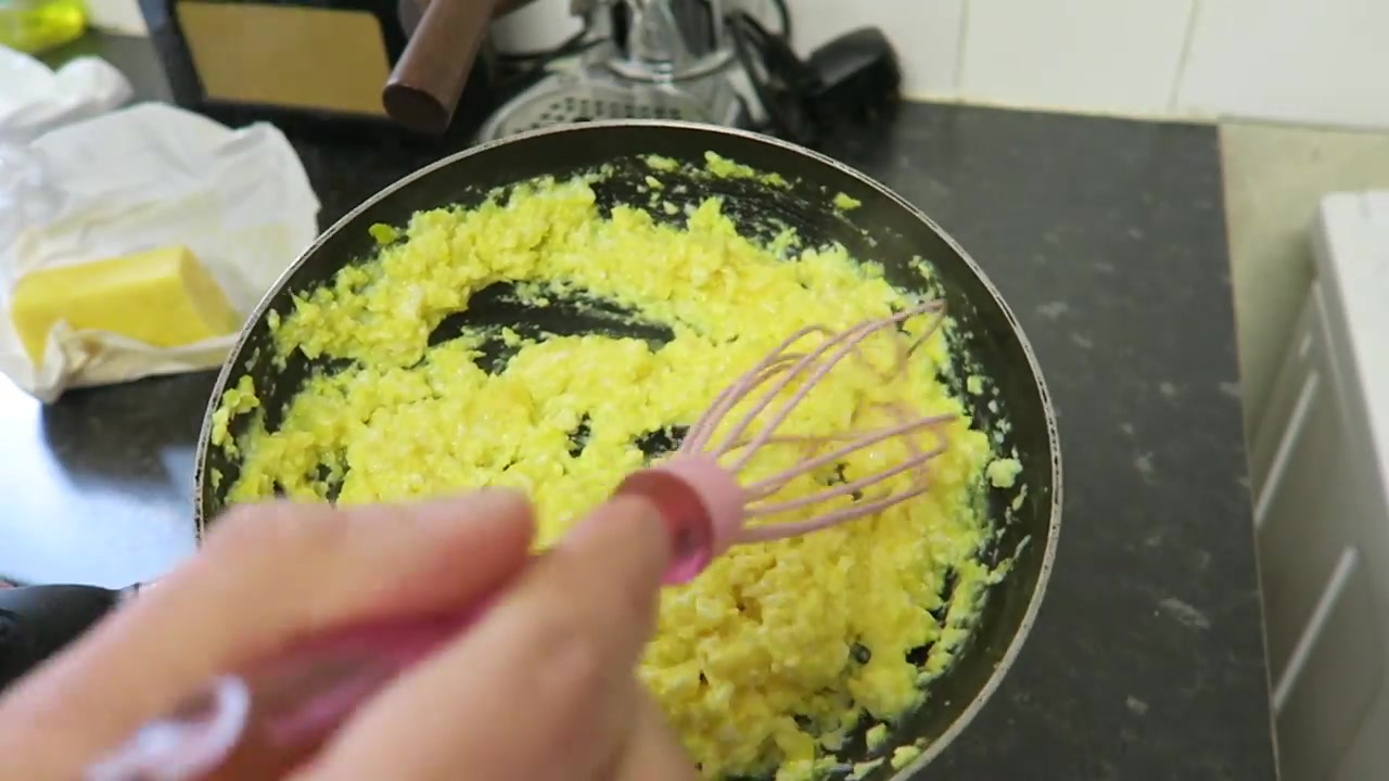Soft scrambled eggs being stirred in a frying pan