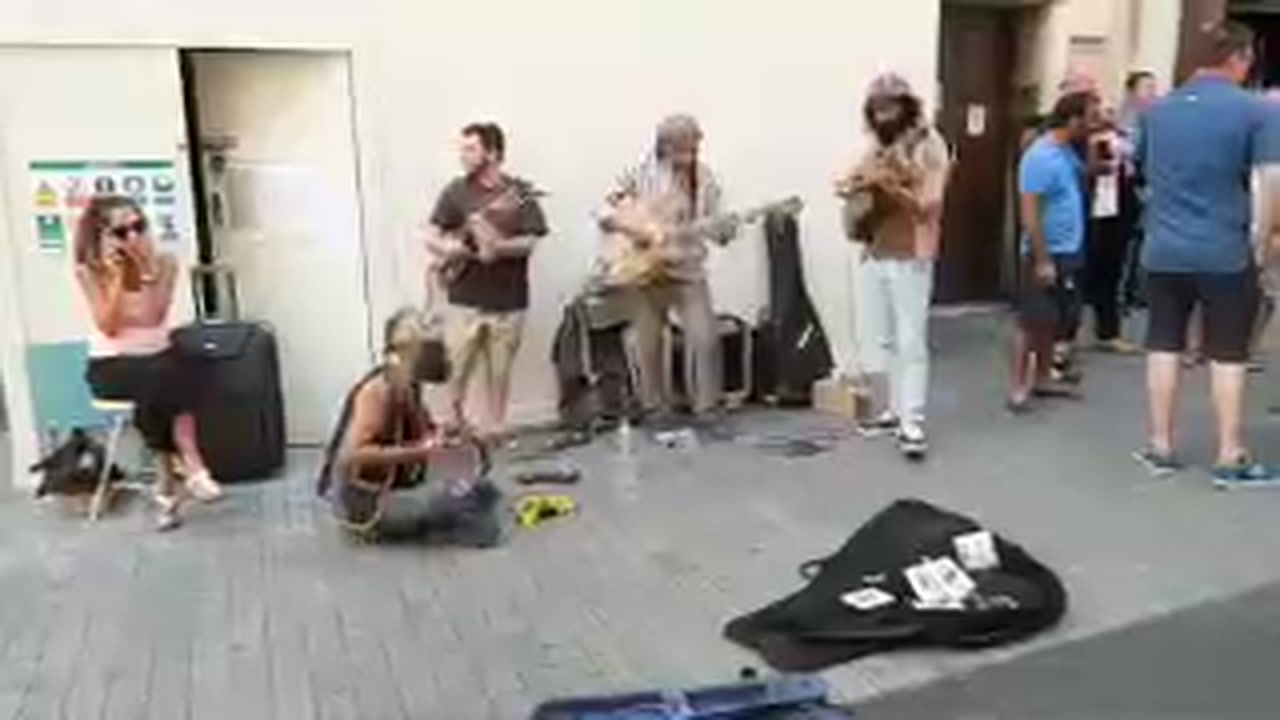 A small band performing on a London pavement as people stop beside them.