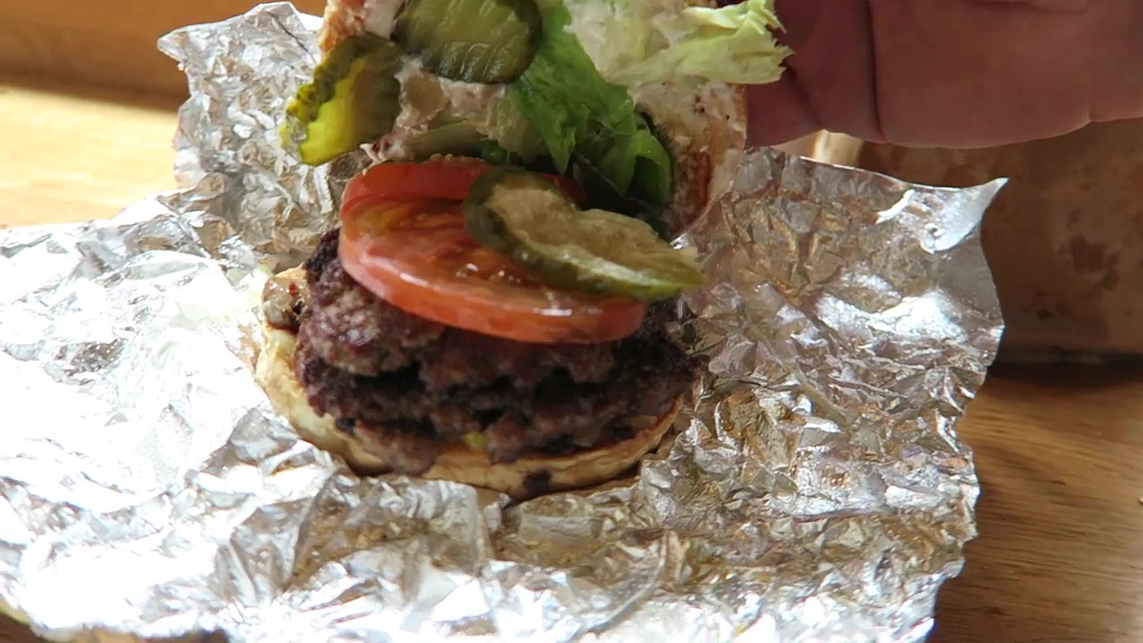Double-patty Five Guys burger with lettuce, tomato and pickles