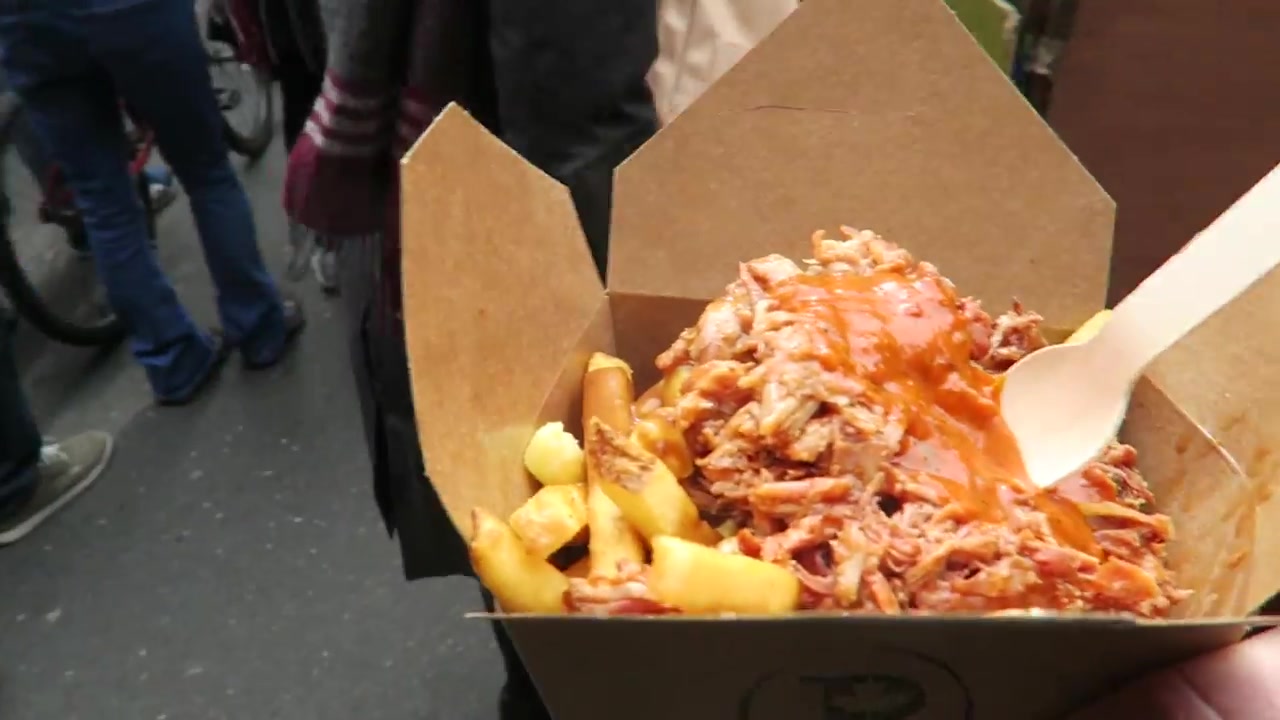 Cardboard box of poutine topped with shredded rib meat and sauce