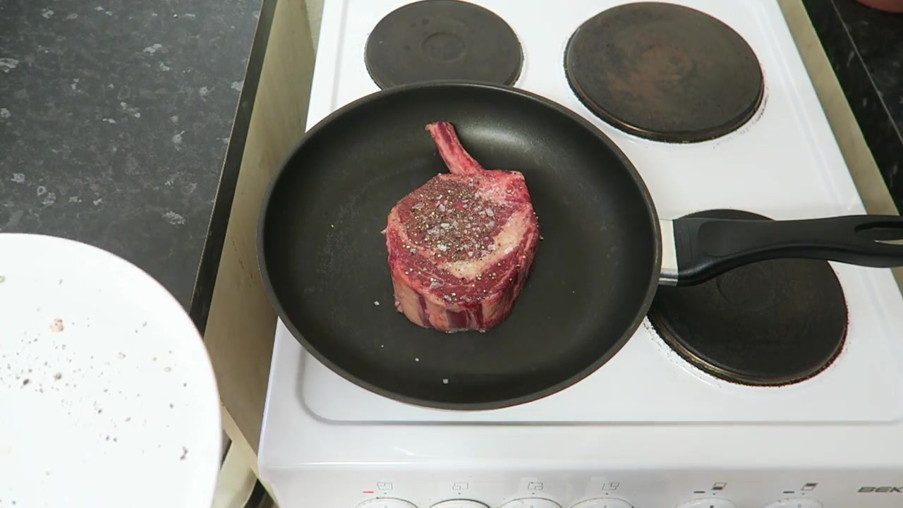 Bone-in rib steak placed in a very hot dry frying pan