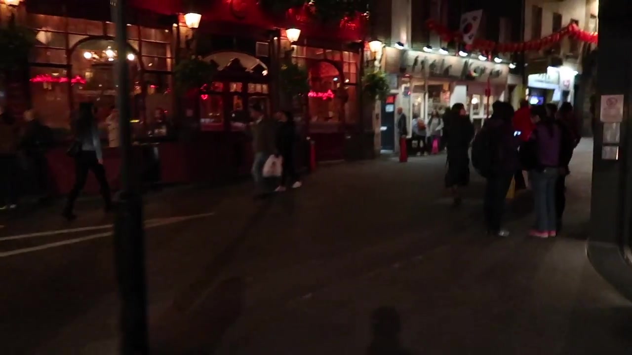 Lantern-lined London Chinatown street with restaurants and pedestrians after dark