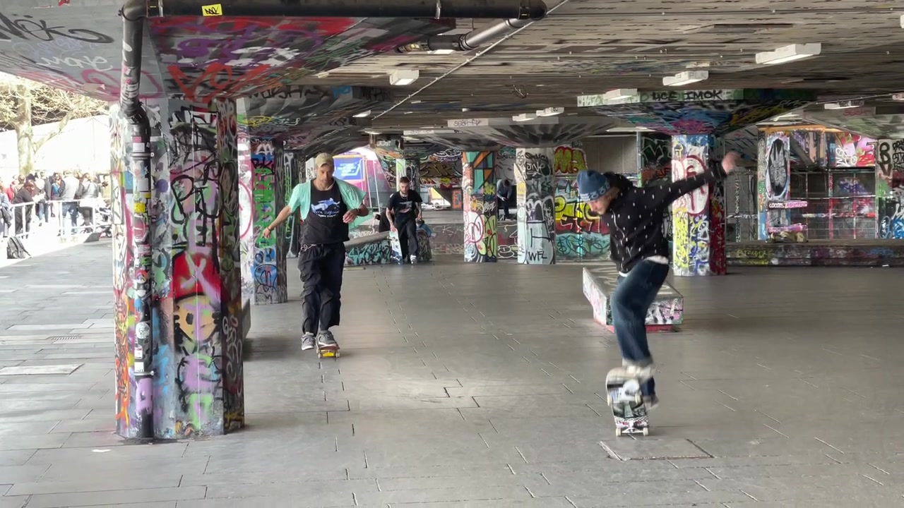 Skateboarder performing a trick among graffiti-covered pillars in the Southbank Undercroft.