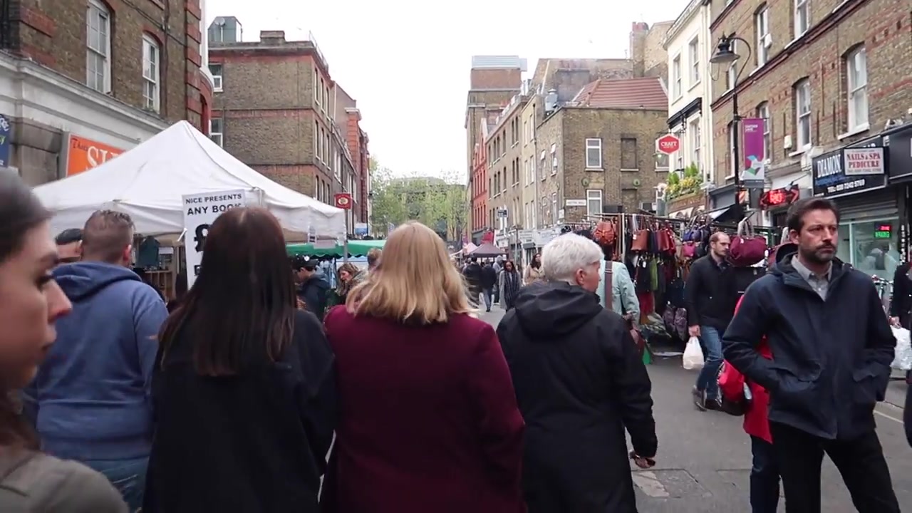 Crowds walking between food and retail stalls at Leather Lane Market