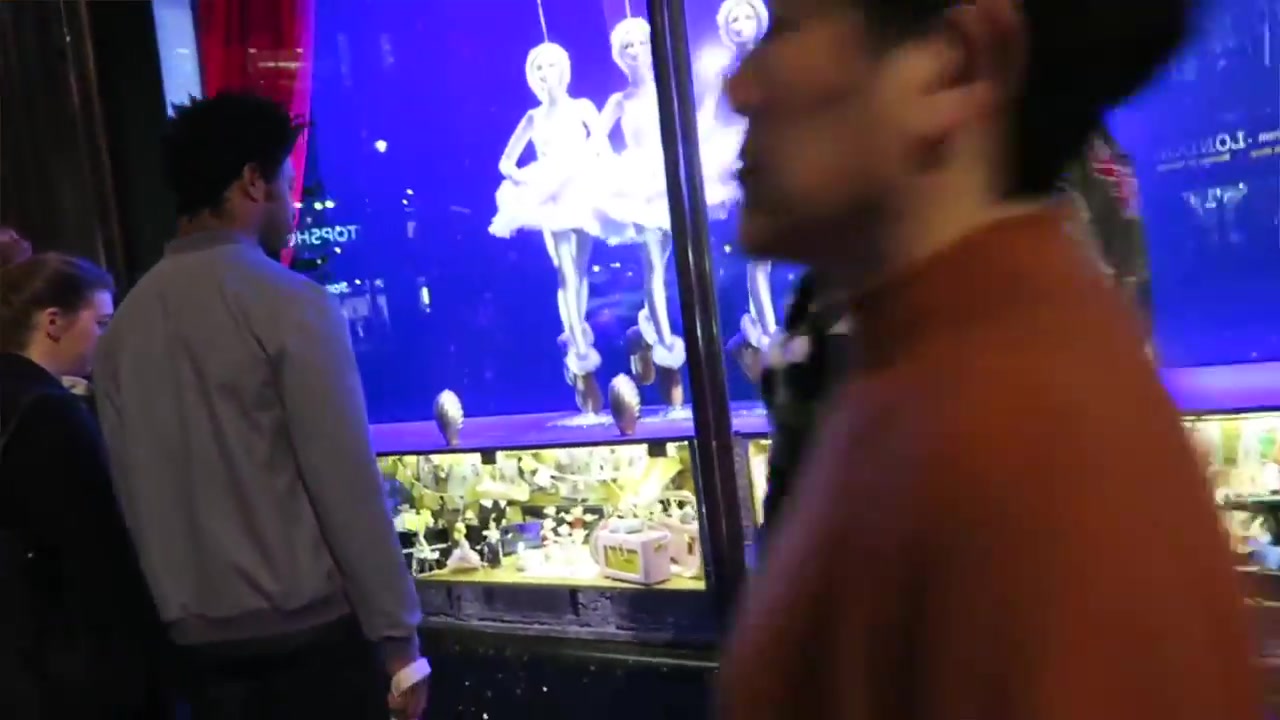 Shoppers looking at a colourful London Christmas window display