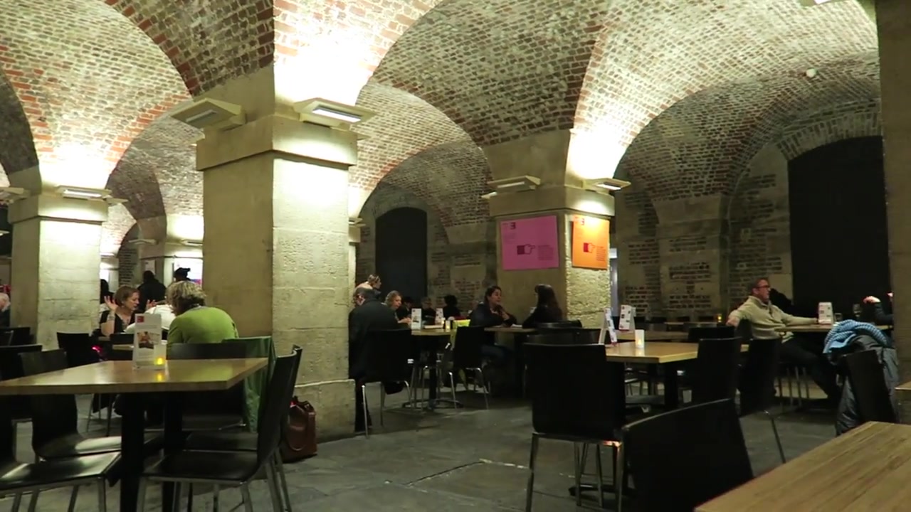 Café tables and visitors beneath the vaulted brick ceiling of Café in the Crypt