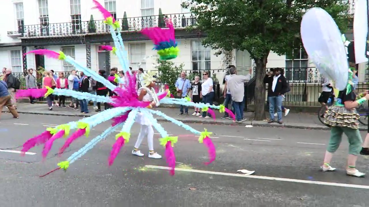 Masquerader wearing a large pink and white feathered costume
