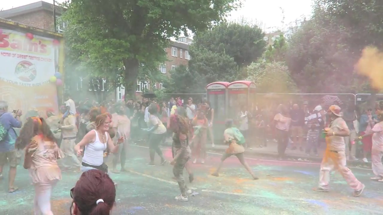 Carnival participants dancing through clouds of coloured powder