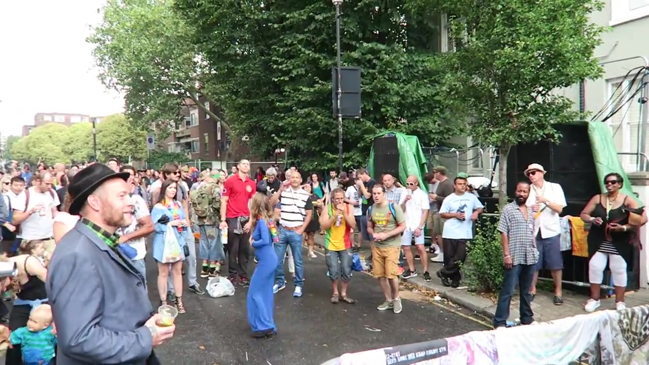 Street performer entertaining a crowd behind barriers at Notting Hill Carnival