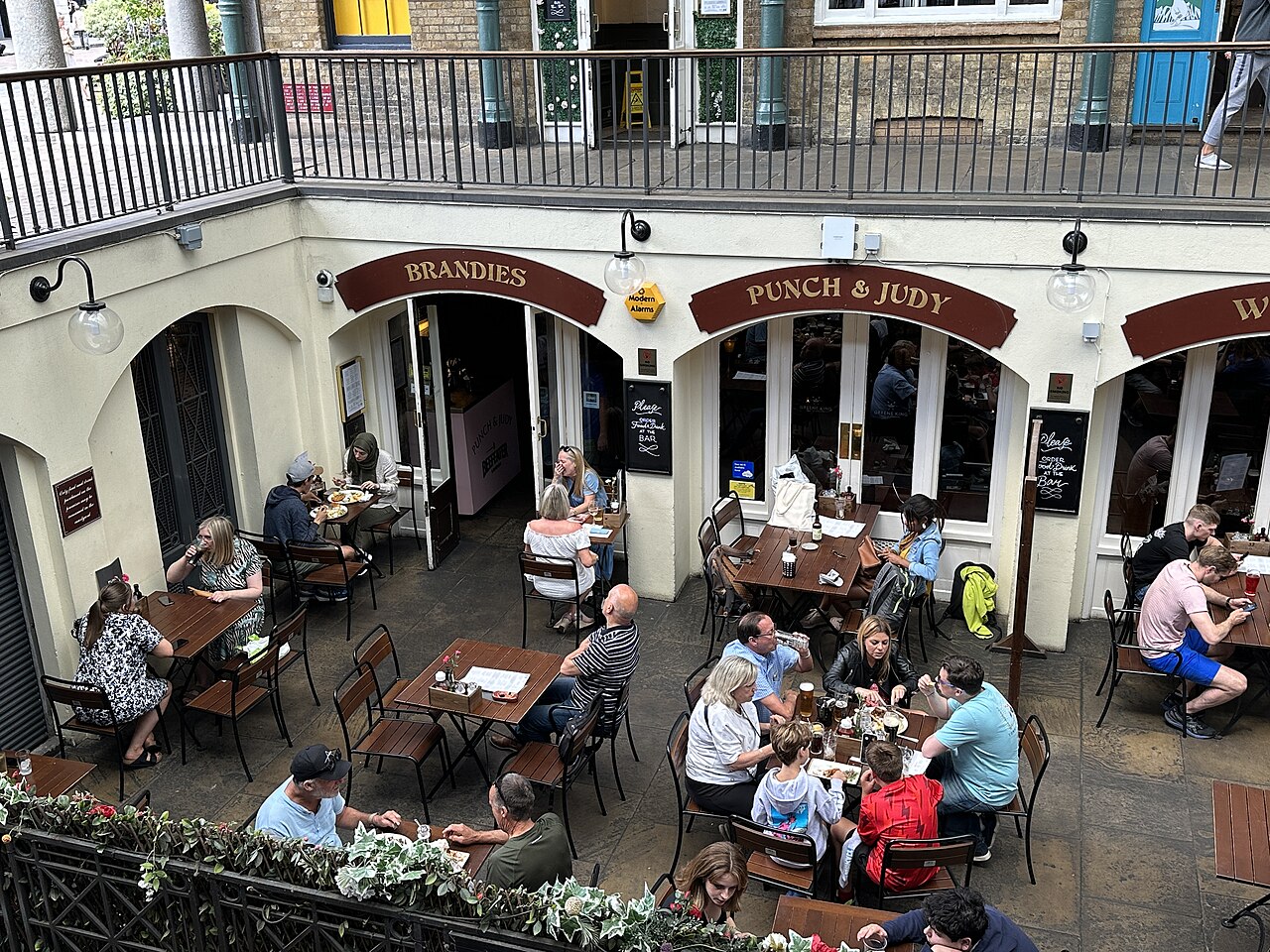 Drinkers at the Punch & Judy pub courtyard beneath the Covent Garden Market balcony