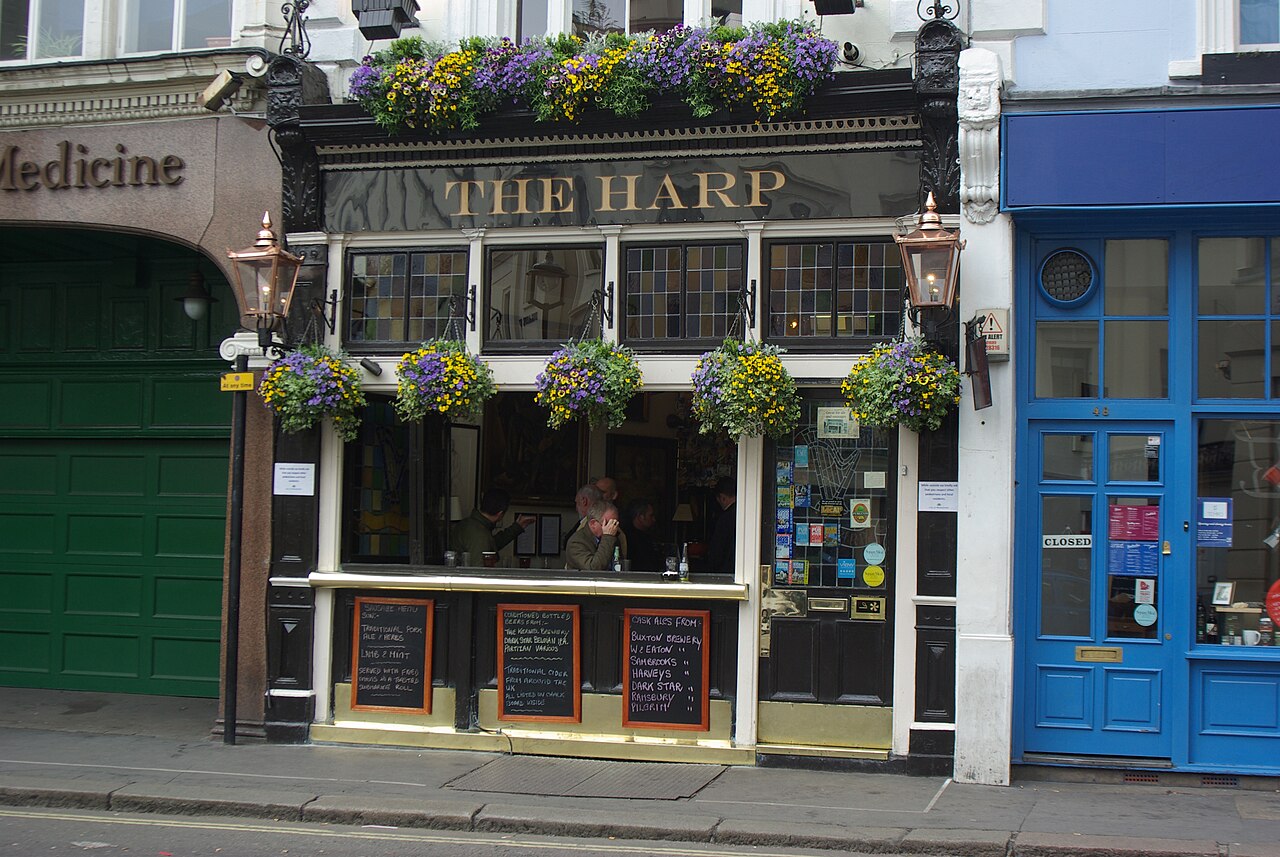 The flower-covered black frontage of The Harp on Chandos Place, Covent Garden
