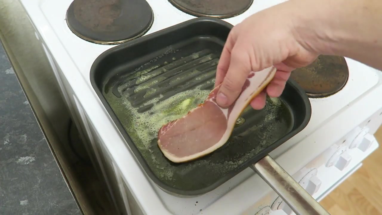 Butter being added to a griddle pan before cooking bacon