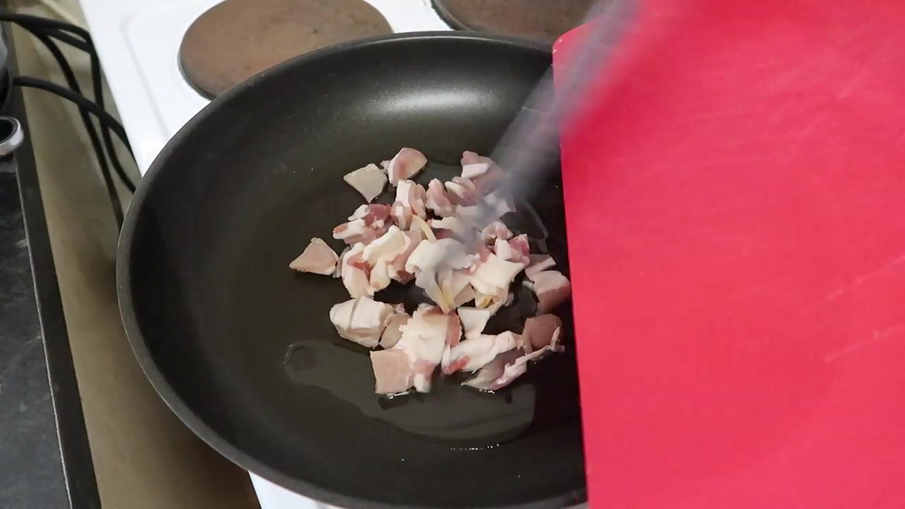 Chopped smoked bacon beginning to cook in a frying pan