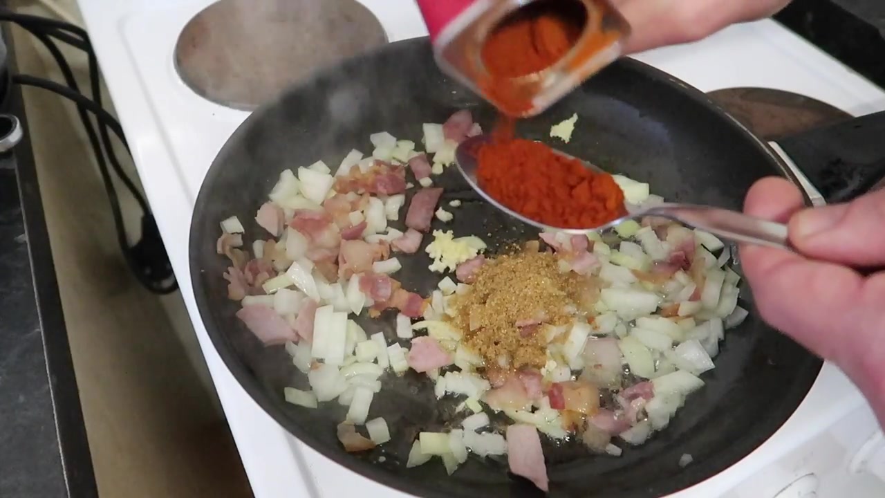 Onion, smoked bacon and paprika cooking in a frying pan