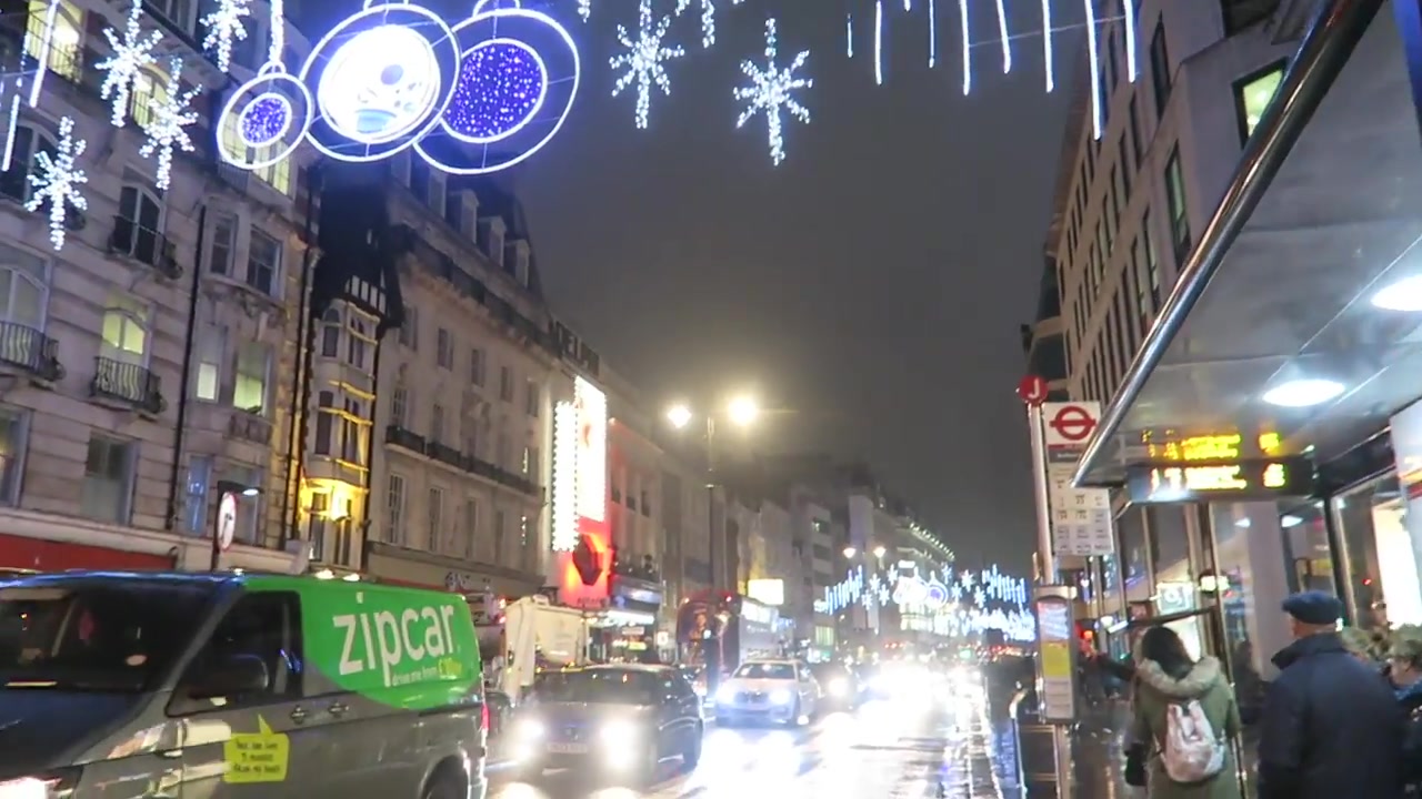 White and blue Christmas lights above wet traffic on the Strand in London